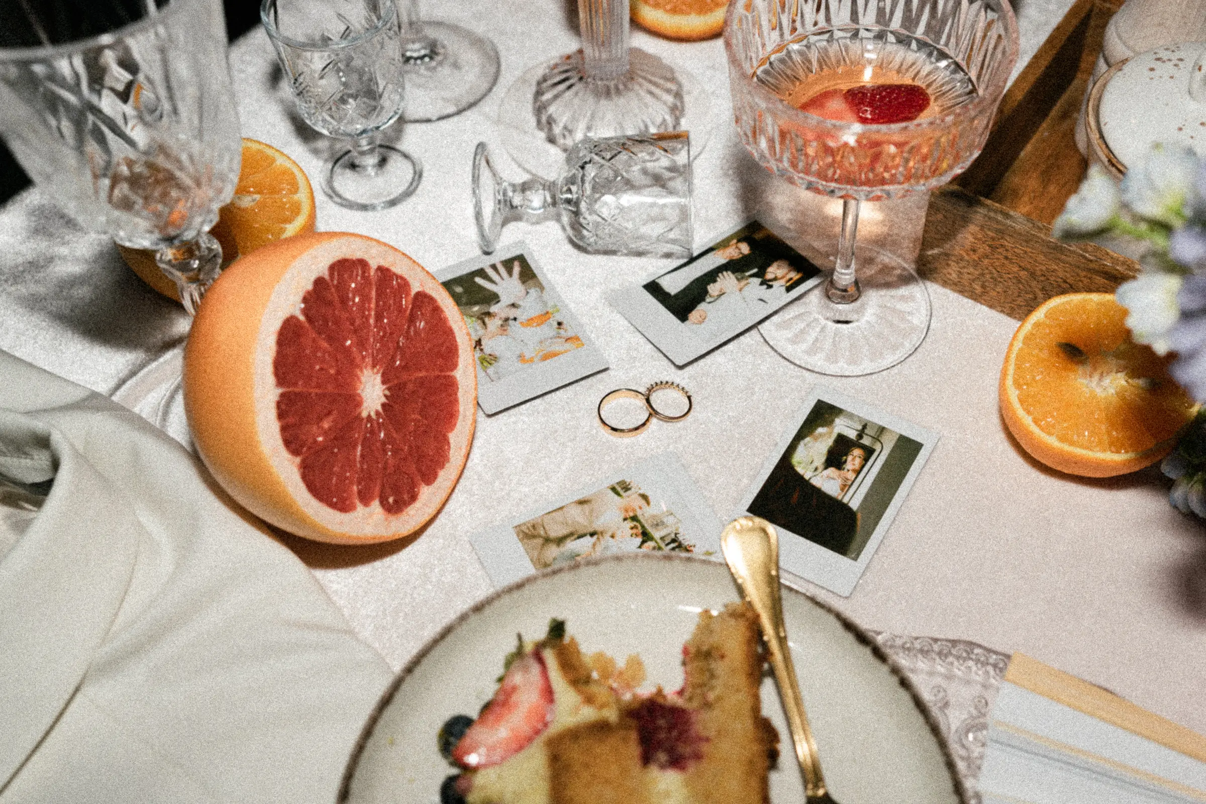 Detale ślubne — kieliszki, owoce i polaroidy na stole weselnym